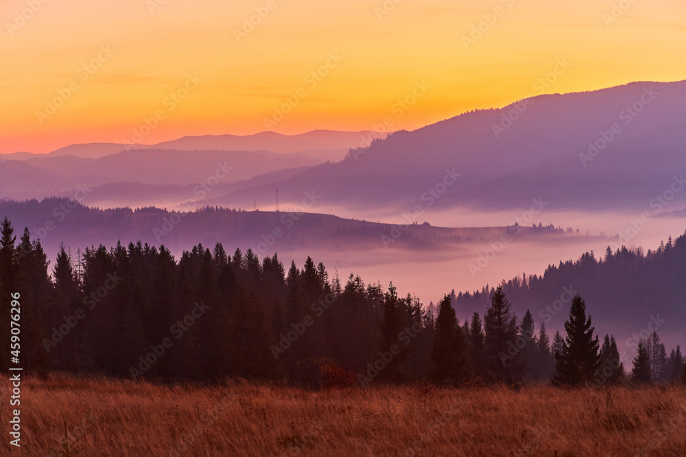 Beautiful autumn sunrise in the mountains. Fog spreads in the lowlands in October