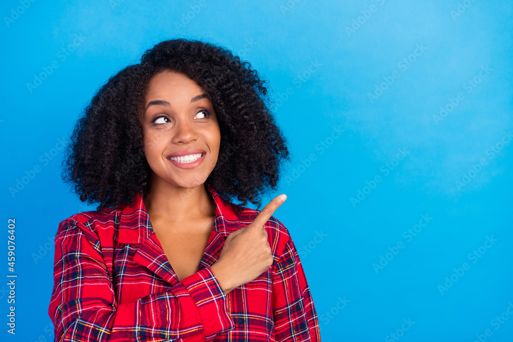 Photo of funky young brunette lady indicate look empty space wear red checkered pajama isolated on blue color background Photo of funky young brunette lady indicate look empty space wear red checkered pajama isolated on blue color background