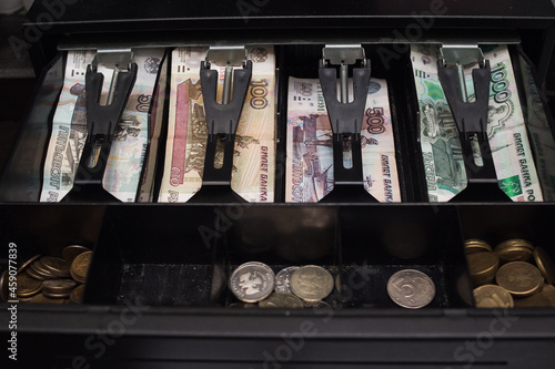 Banknotes and coins of the Russian ruble inside the cash register