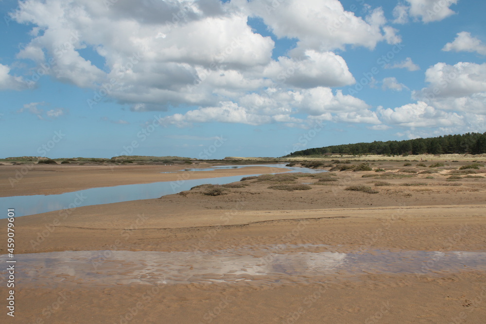 Beautiful landscape of the vast sandy beach at Holkham in Norfolk East Anglia with white puffy clouds in blue skies in Summer holiday day time