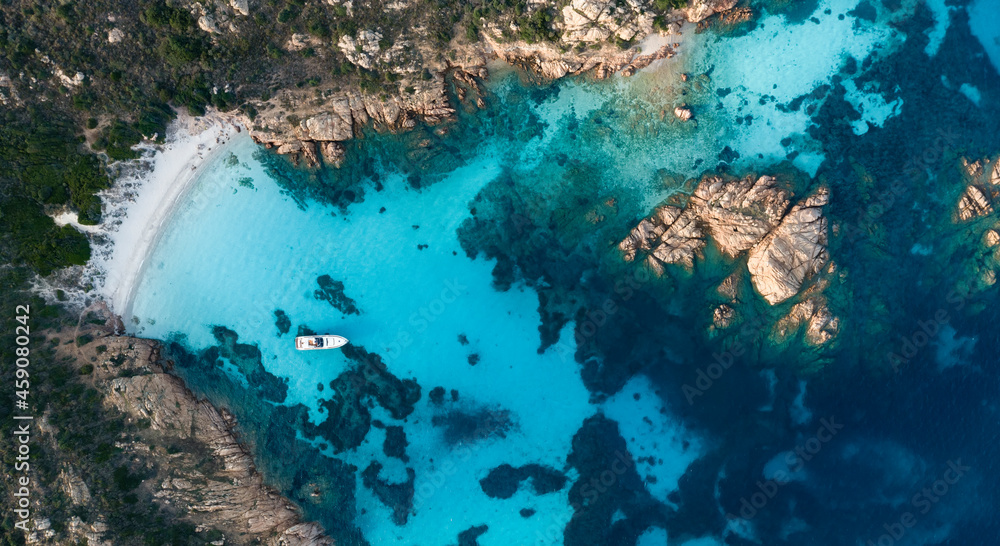 View from above, stunning aerial view of Mortorio island with a beautiful white sand beach and a boat floating on a turquoise water. Sardinia, Italy.