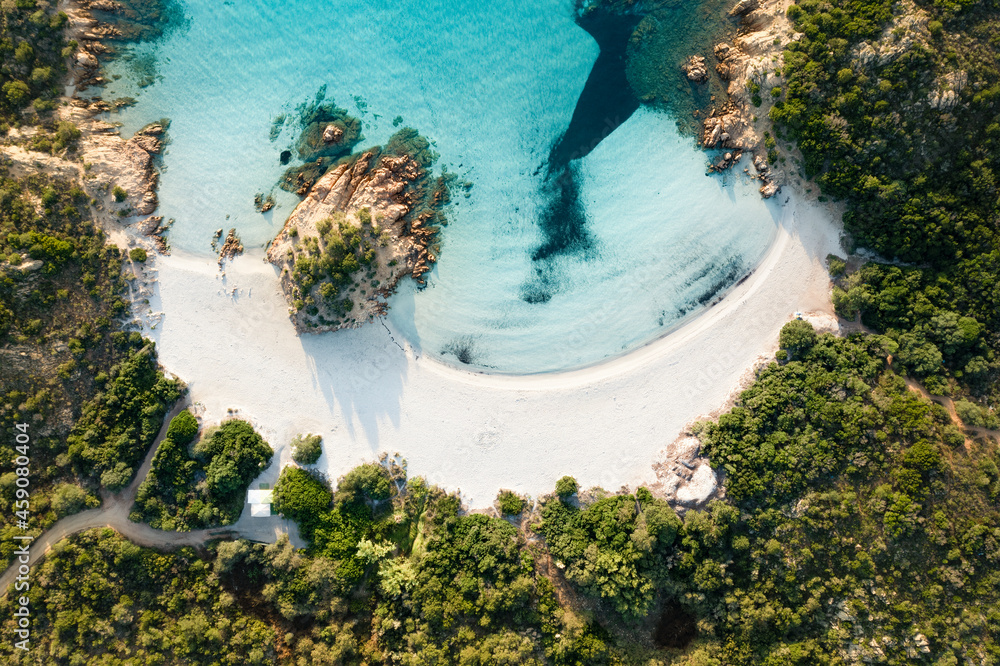 View from above, stunning aerial view of a green coast with the beautiful Prince Beach (Spiaggia del Principe) a white sand beach bathed by a turquoise water. Sardinia, Italy.
