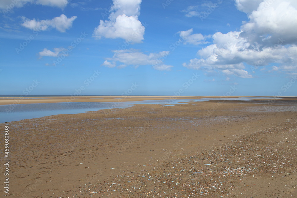Beautiful landscape of the vast sandy beach at Holkham in Norfolk East Anglia with white puffy clouds in blue skies in Summer holiday day time Beautiful landscape of the vast sandy beach at Holkham in Norfolk East Anglia with white puffy clouds in blue skies in Summer holiday day time