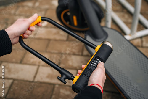 Women's hands hold the code bike u lock so that the electric scooter is not stolen, leave it safe, protected.