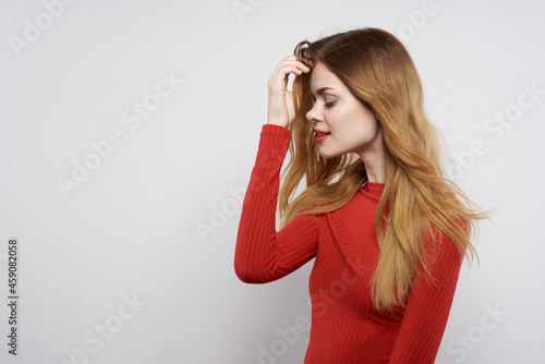 cheerful woman in red dress posing luxury hand gesture light background