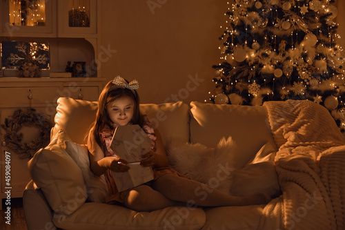 Adorable little girl opening a magical Christmas gift