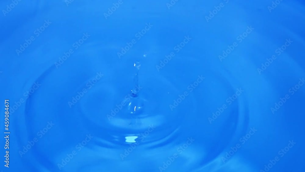 Waterdrops falling onto the blue surface of water, splashing more droplets and creating ripples Waterdrops falling onto the blue surface of water, splashing more droplets and creating ripples