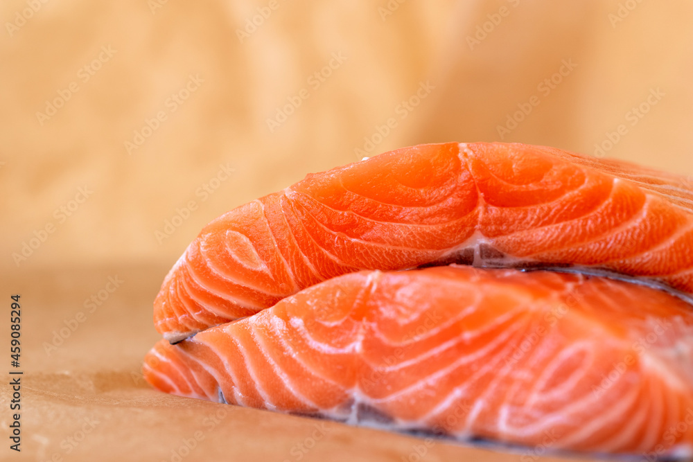 Close up of two fresh raw salmon fillet slices on baking paper Close up of two fresh raw salmon fillet slices on baking paper