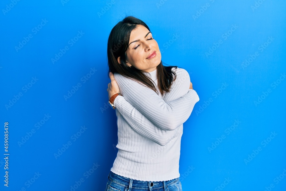 Young hispanic woman wearing casual clothes hugging oneself happy and positive, smiling confident. self love and self care Young hispanic woman wearing casual clothes hugging oneself happy and positive, smiling confident. self love and self care
