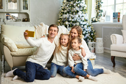 happy family sitting in living room and taking selfie with smartphone