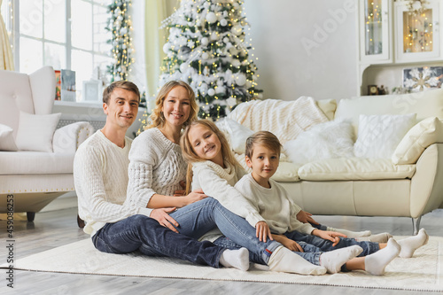 Happy family in white sweaters sitting on the living room floor