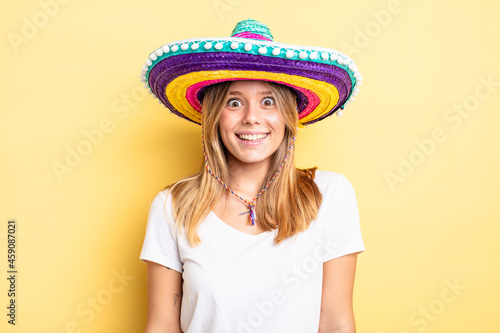 pretty blonde girl looking happy and pleasantly surprised. mexican hat concept
