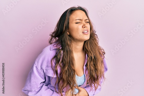 Young hispanic girl wearing casual clothes with hand on stomach because nausea  painful disease feeling unwell. ache concept.