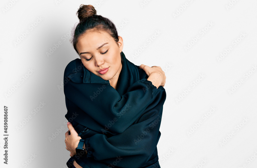 Young hispanic girl wearing sportswear hugging oneself happy and positive, smiling confident. self love and self care Young hispanic girl wearing sportswear hugging oneself happy and positive, smiling confident. self love and self care