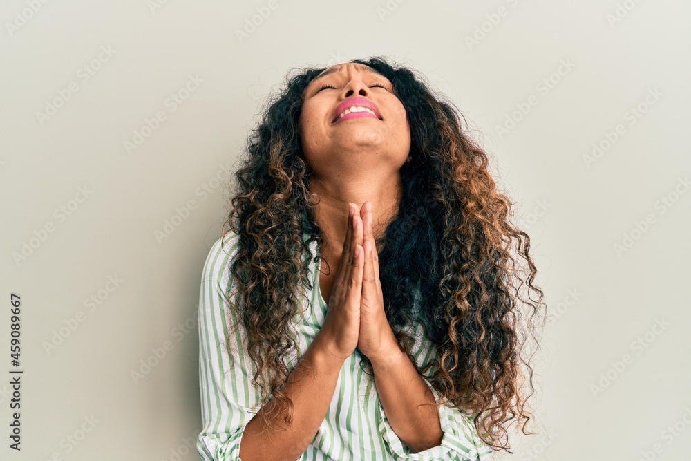 Young latin woman wearing casual clothes begging and praying with hands together with hope expression on face very emotional and worried. begging. Young latin woman wearing casual clothes begging and praying with hands together with hope expression on face very emotional and worried. begging.