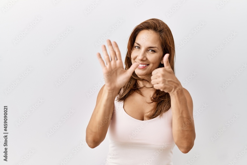 Middle age hispanic woman standing over isolated background showing and pointing up with fingers number six while smiling confident and happy. Middle age hispanic woman standing over isolated background showing and pointing up with fingers number six while smiling confident and happy.