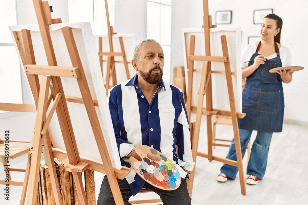 Senior artist man at art studio relaxed with serious expression on face. simple and natural looking at the camera.