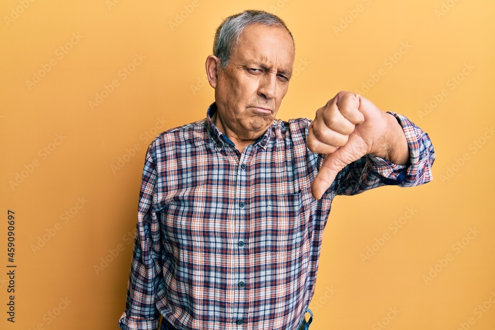 Handsome senior man with grey hair wearing casual shirt looking unhappy and angry showing rejection and negative with thumbs down gesture. bad expression. Handsome senior man with grey hair wearing casual shirt looking unhappy and angry showing rejection and negative with thumbs down gesture. bad expression.