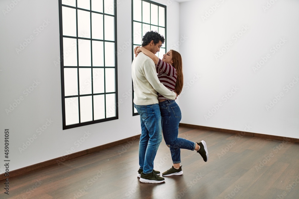 Young hispanic couple smiling happy and hugging standing at empty new home. Young hispanic couple smiling happy and hugging standing at empty new home.