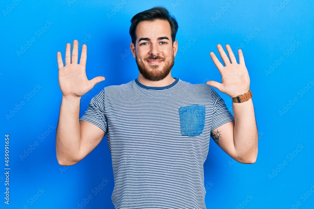 Handsome caucasian man with beard wearing casual striped t shirt showing and pointing up with fingers number ten while smiling confident and happy. Handsome caucasian man with beard wearing casual striped t shirt showing and pointing up with fingers number ten while smiling confident and happy.
