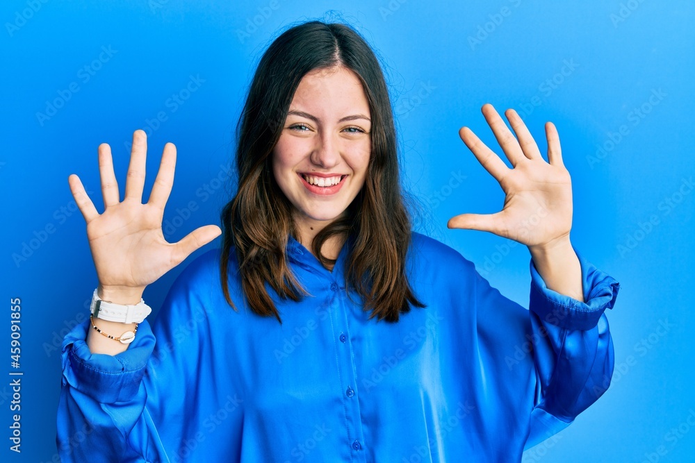 Young brunette woman wearing casual blue shirt showing and pointing up with fingers number ten while smiling confident and happy. Young brunette woman wearing casual blue shirt showing and pointing up with fingers number ten while smiling confident and happy.