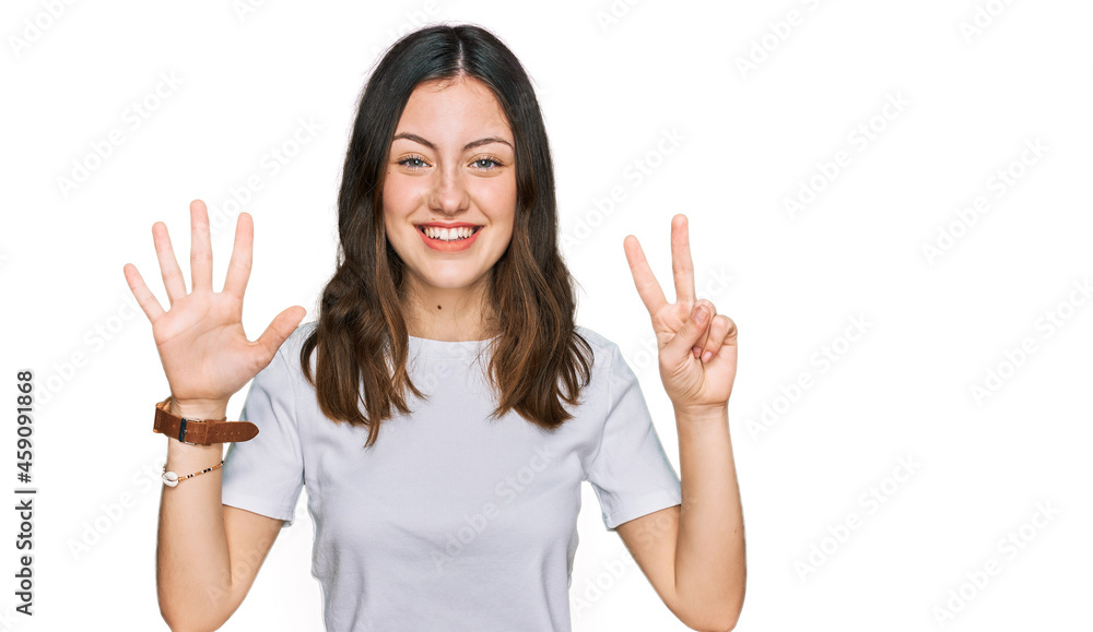 Young beautiful woman wearing casual white t shirt showing and pointing up with fingers number seven while smiling confident and happy. Young beautiful woman wearing casual white t shirt showing and pointing up with fingers number seven while smiling confident and happy.