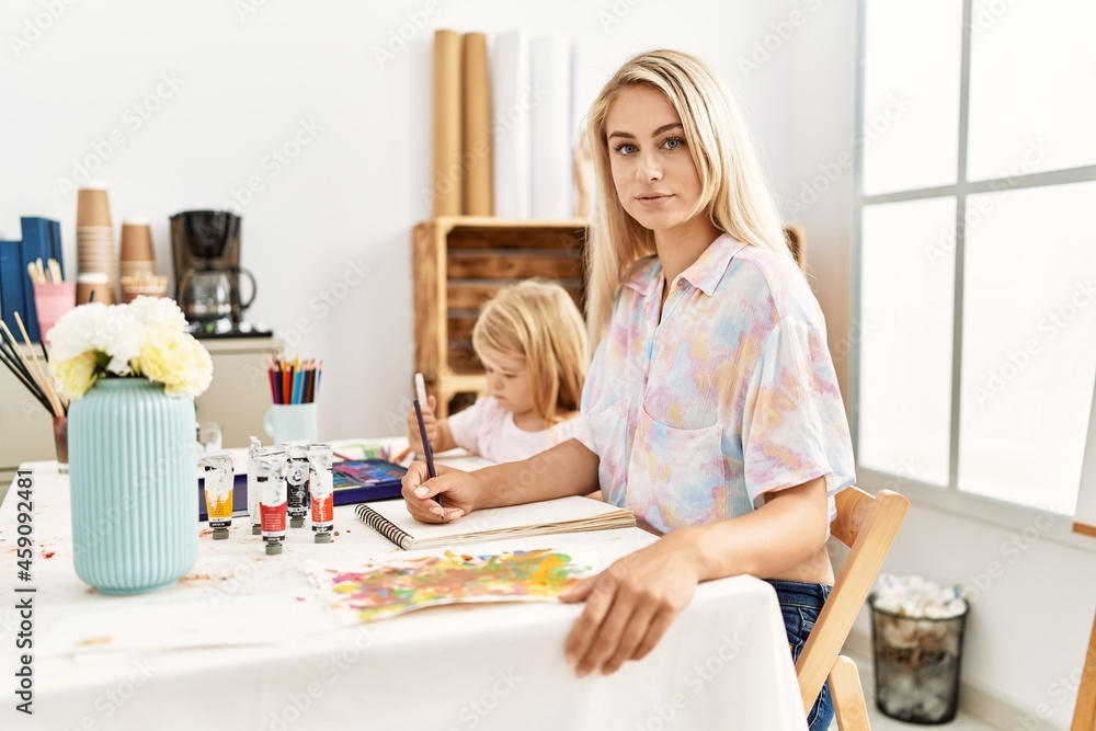Caucasian family of mother and daughter painting at art studio thinking attitude and sober expression looking self confident Caucasian family of mother and daughter painting at art studio thinking attitude and sober expression looking self confident
