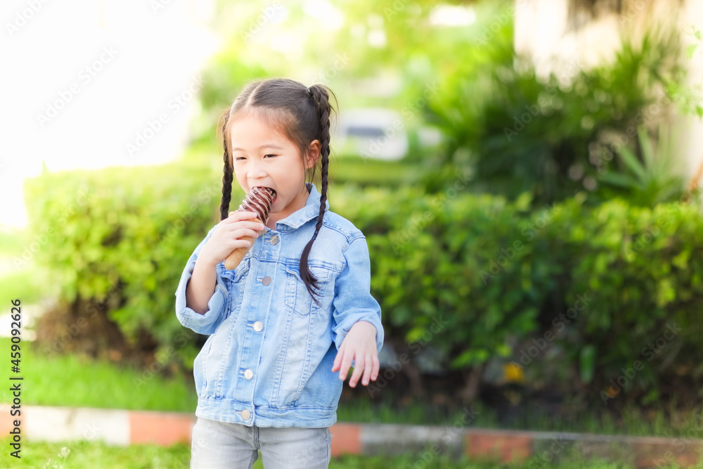 Little asia child girl eat ice cream in a park nature green background, happy time Little asia child girl eat ice cream in a park nature green background, happy time