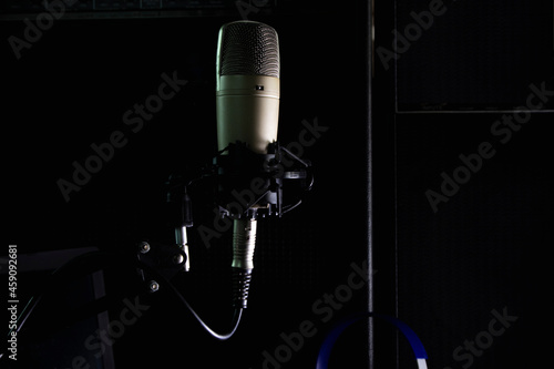 Condenser microphone on stand with background audio equipment.