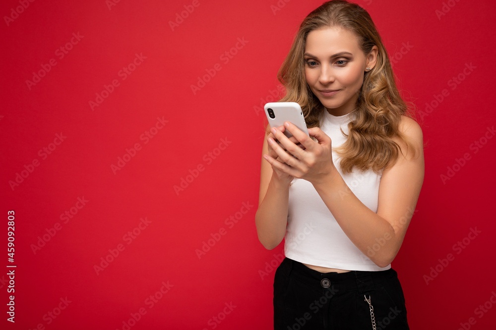 Beautiful young woman wearing casual clothes standing isolated over background surfing on the internet via phone looking at mobile screen Beautiful young woman wearing casual clothes standing isolated over background surfing on the internet via phone looking at mobile screen