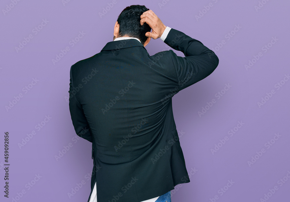 Handsome hispanic man wearing business clothes backwards thinking about doubt with hand on head