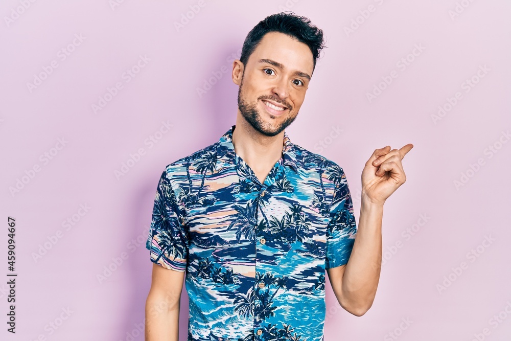 Young hispanic man wearing casual clothes smiling happy pointing with hand and finger to the side Young hispanic man wearing casual clothes smiling happy pointing with hand and finger to the side