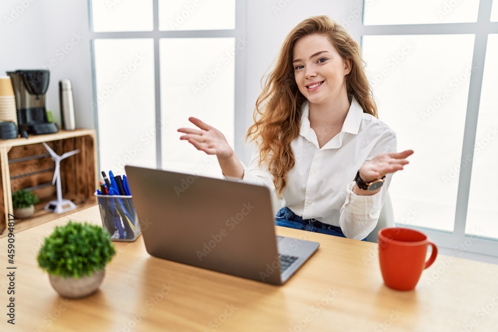 Young caucasian woman working at the office using computer laptop smiling cheerful offering hands giving assistance and acceptance. Young caucasian woman working at the office using computer laptop smiling cheerful offering hands giving assistance and acceptance.