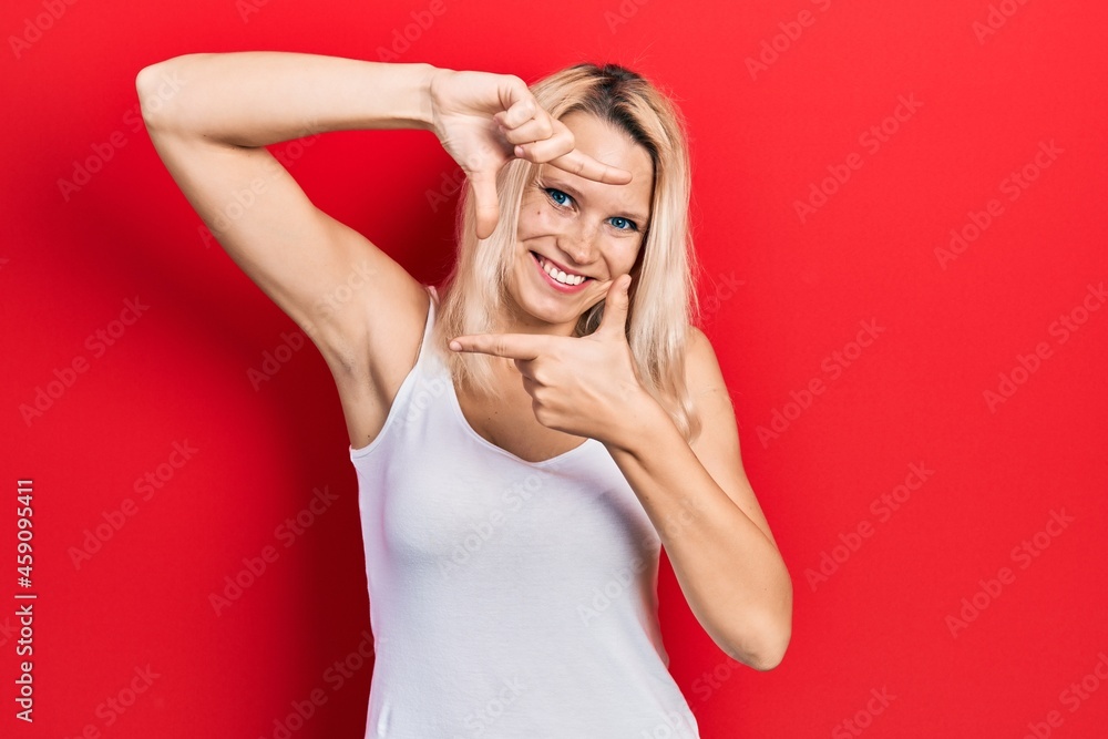 Beautiful caucasian blonde woman wearing casual white t shirt smiling making frame with hands and fingers with happy face. creativity and photography concept. Beautiful caucasian blonde woman wearing casual white t shirt smiling making frame with hands and fingers with happy face. creativity and photography concept.