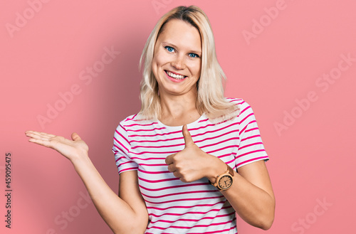 Young caucasian woman wearing casual clothes showing palm hand and doing ok gesture with thumbs up, smiling happy and cheerful © Krakenimages.com