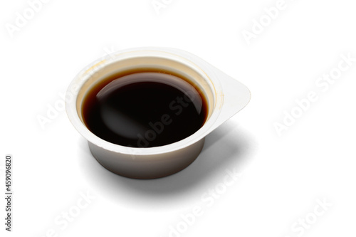 Plastic open disposable container with soy sauce. Isolated on a white background with a shadow, close-up