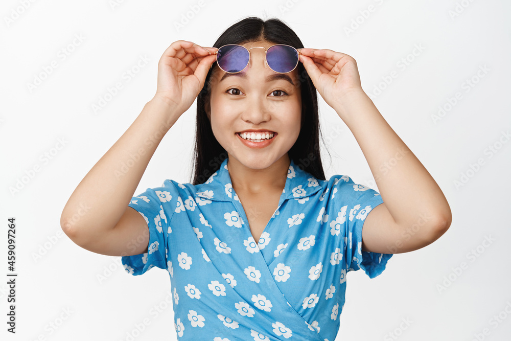 Portrait of happy beautiful korean girl takes off sunglasses, looking enthusiastic at camera with big smile, standing over white background Portrait of happy beautiful korean girl takes off sunglasses, looking enthusiastic at camera with big smile, standing over white background