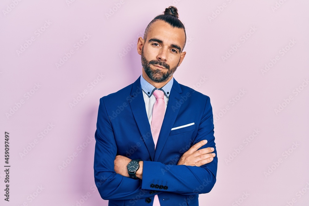 Young hispanic man wearing business suit with arms crossed gesture relaxed with serious expression on face. simple and natural looking at the camera. Young hispanic man wearing business suit with arms crossed gesture relaxed with serious expression on face. simple and natural looking at the camera.