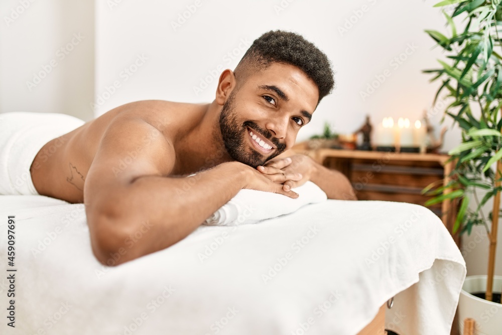 Young african american smiling happy relaxed lying on massage table at beauty center. Young african american smiling happy relaxed lying on massage table at beauty center.