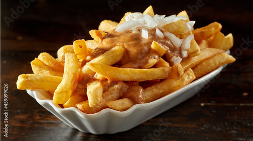 Tasty fries with chopped raw onion and sauce in bowl