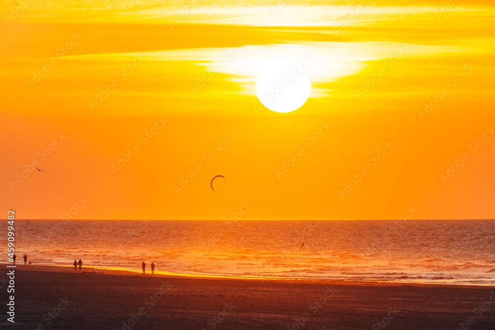 setting sun in the sea, on the beach of Ameland, north sea, wadden sea, beautiful warm golden and yellow colors 