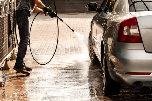 Young man washes a car at a self-service car wash. © Maryana