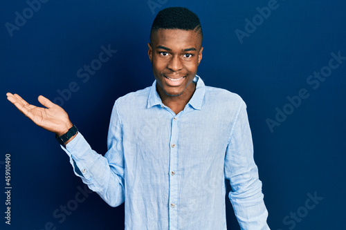 Young african american man wearing casual clothes smiling cheerful presenting and pointing with palm of hand looking at the camera.