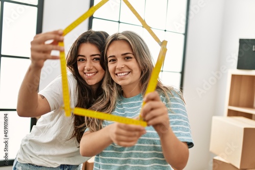 Young beautiful couple smiling happy holding house project at new home.