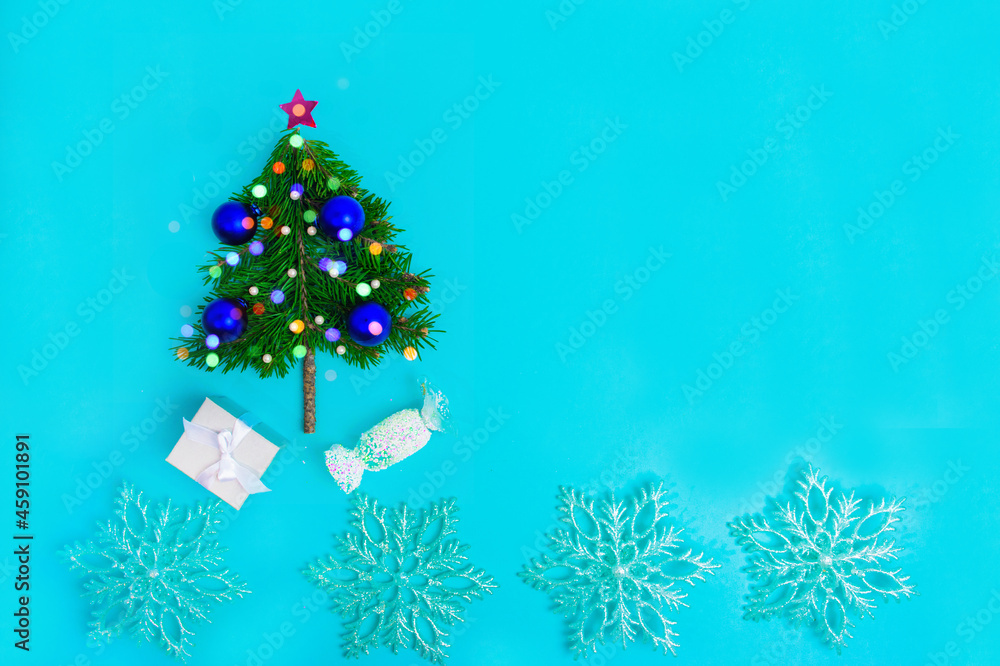 Small Christmas tree decorated with blue balls on turquoise background. Holiday greeting card