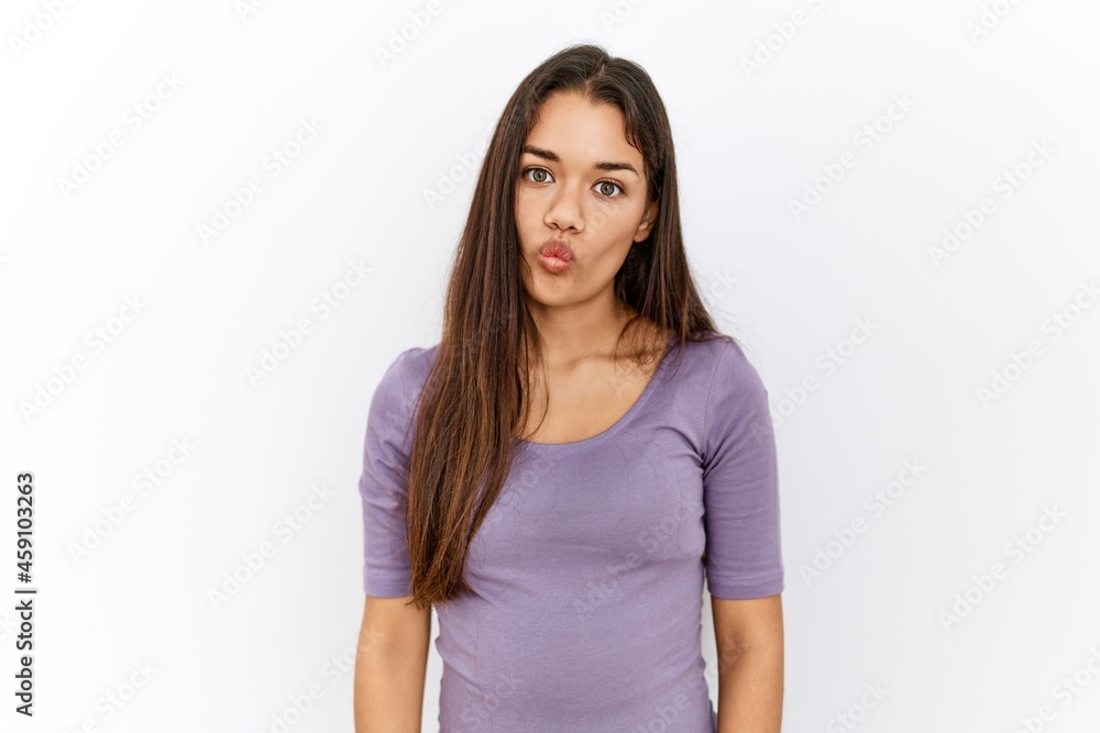 Young brunette woman standing by isolated background making fish face with lips, crazy and comical gesture. funny expression. Young brunette woman standing by isolated background making fish face with lips, crazy and comical gesture. funny expression.