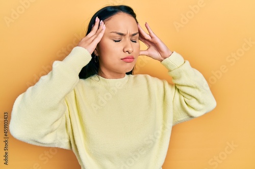 Beautiful hispanic woman with nose piercing wearing casual yellow sweater with hand on head, headache because stress. suffering migraine. © Krakenimages.com