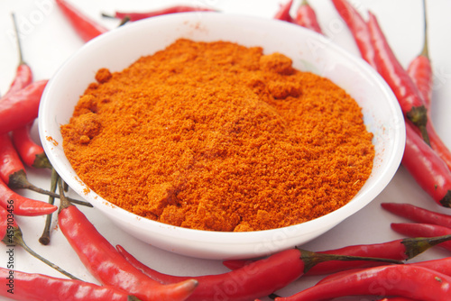 Chili powder and red peppers on table background.