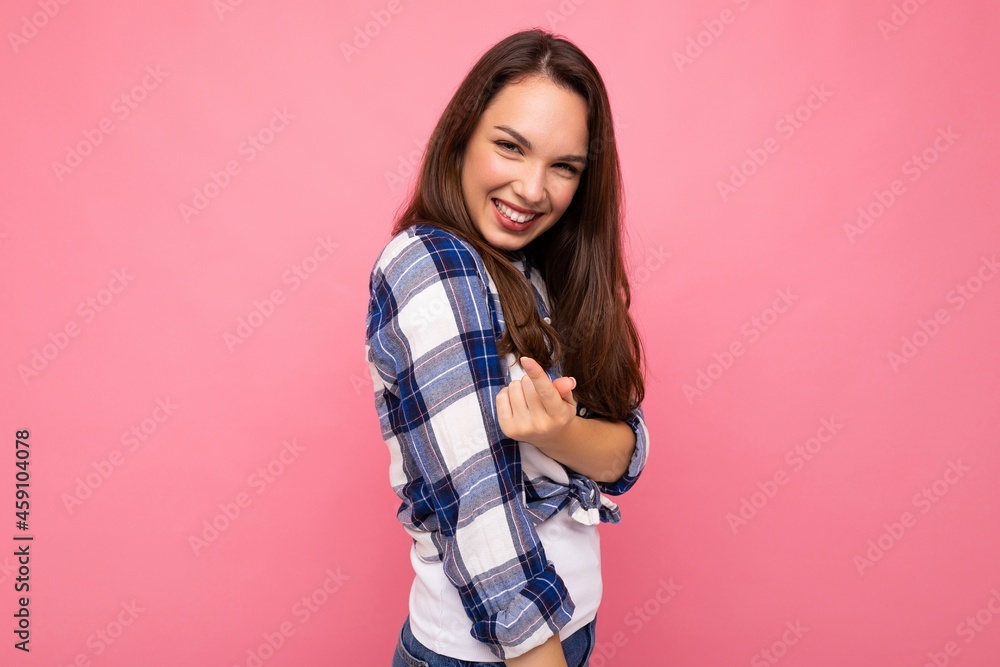 Photo portrait of young beautiful smiling hipster brunette woman in trendy blue and white shirt. Sexy carefree female person posing isolated near pink wall with empty space in studio. Positive model