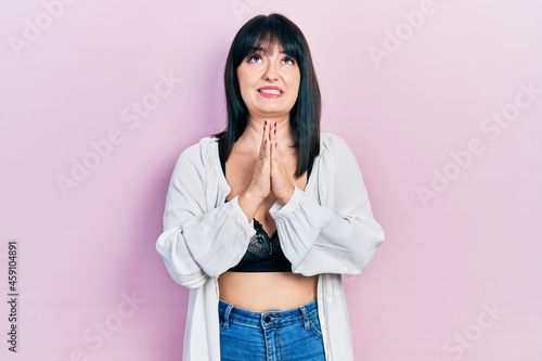 Young hispanic woman wearing lingerie begging and praying with hands together with hope expression on face very emotional and worried. begging.